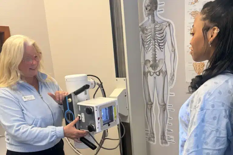 Team member explaining diagnostic X-ray equipment to a patient